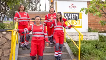 Quatres employés debout devant un panneau Safety First ALPHA CIMENT